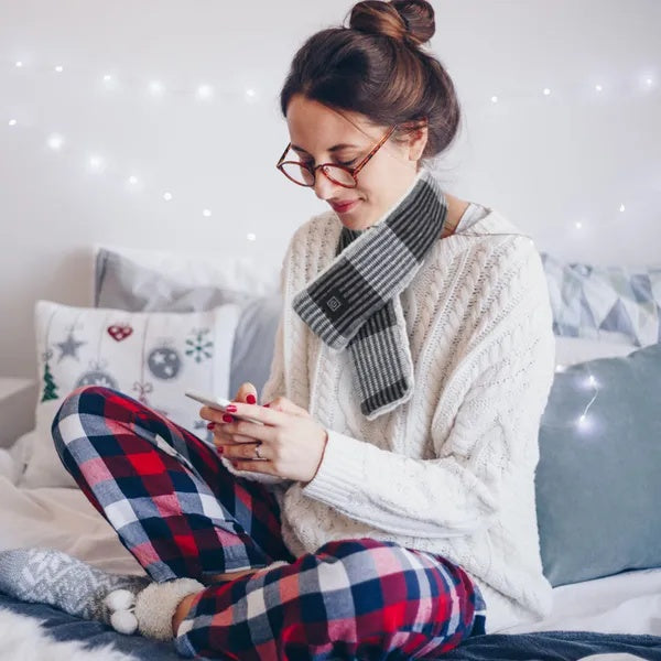 Woman wearing the gray plaid USB Heated Scarf while relaxing at home